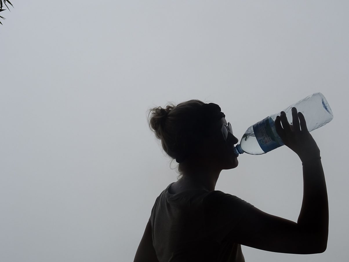 Girl hiking in clouds drinking water