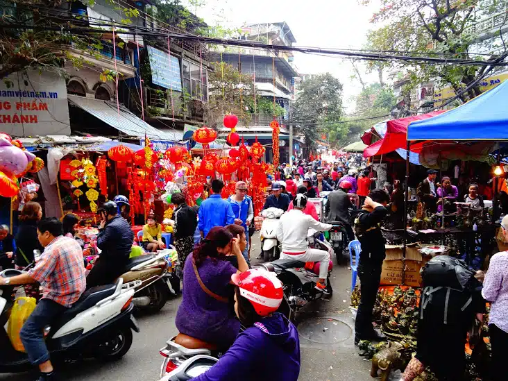 A busy market street in Hanoi filled with mopeds