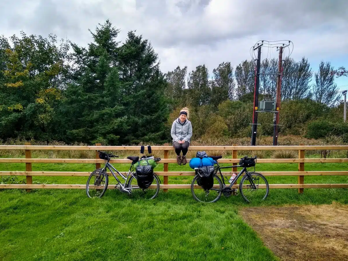 Cycle tour girl sitting with bikes on fence