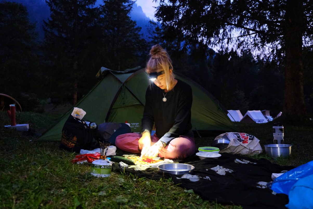 Girl using a Black Diamond headtorch to cook on camping fire