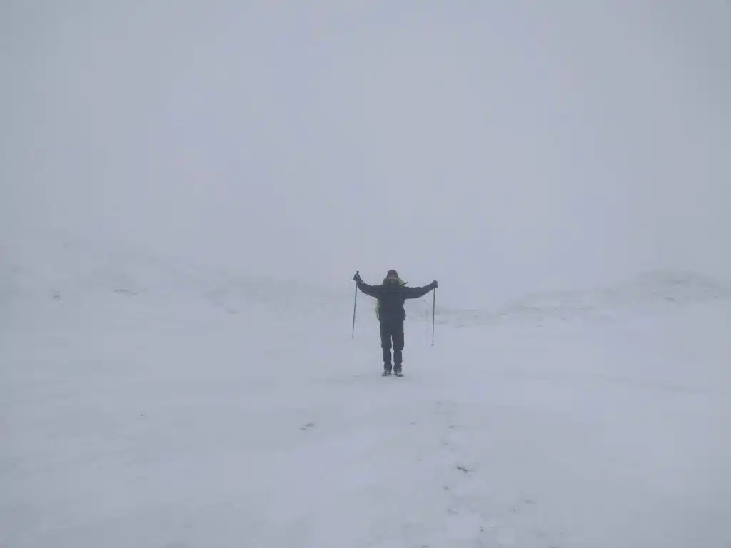 Man hiking in snow in whiteout