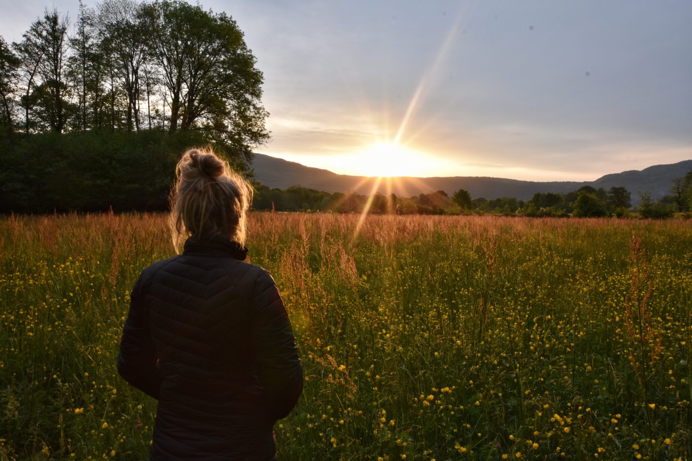 Girl watching sunrise in buttercup field 