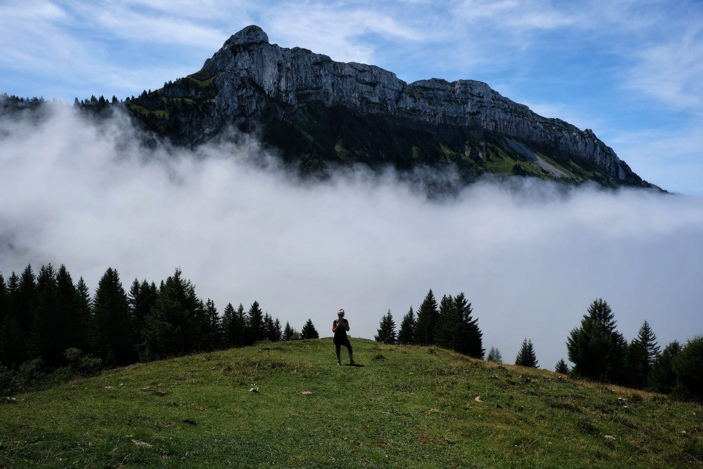 Girl on peak with clouds around 