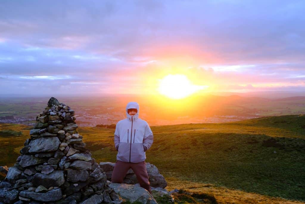 Man on mountain standing in front of incredible sunset