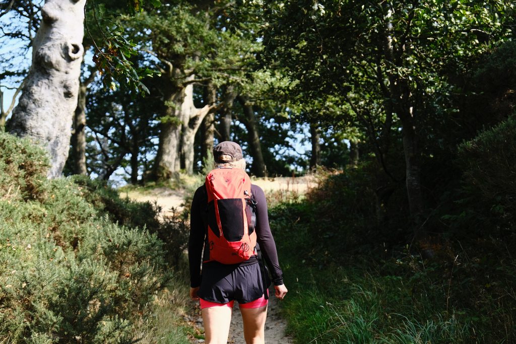 Women wearing a sustainable climbing rucksack hiking through woodland