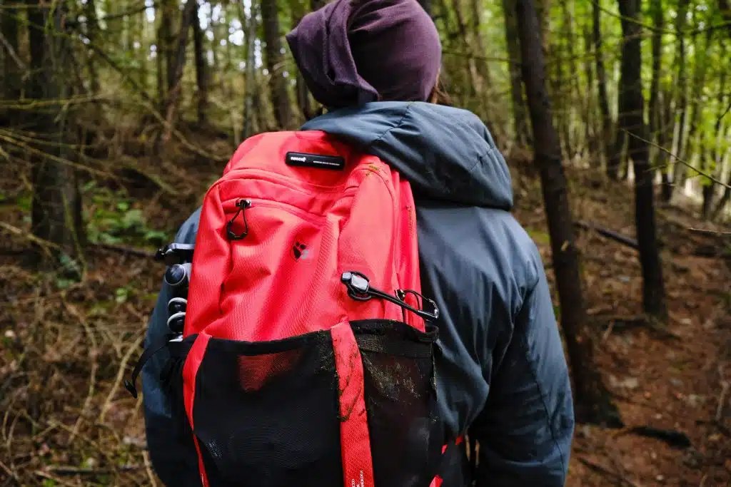 Man wearing wering vegan coat and sustainable rucksack in woods