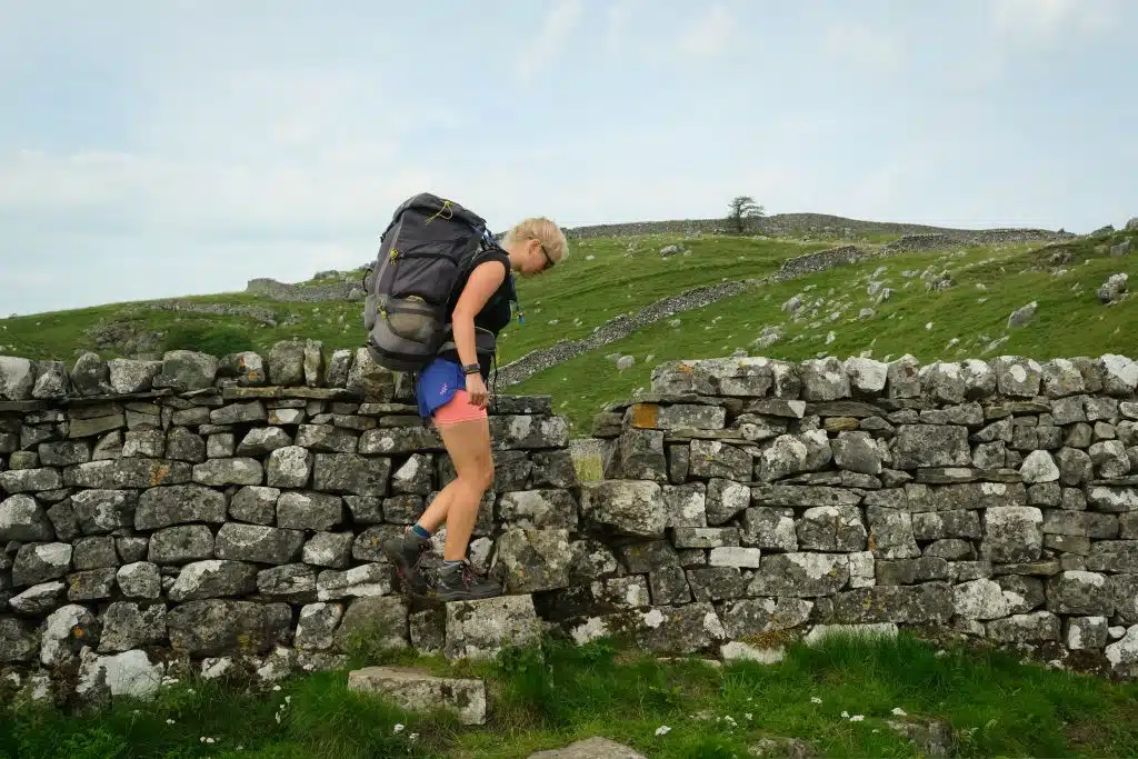 Woman hiking in shorts over wall