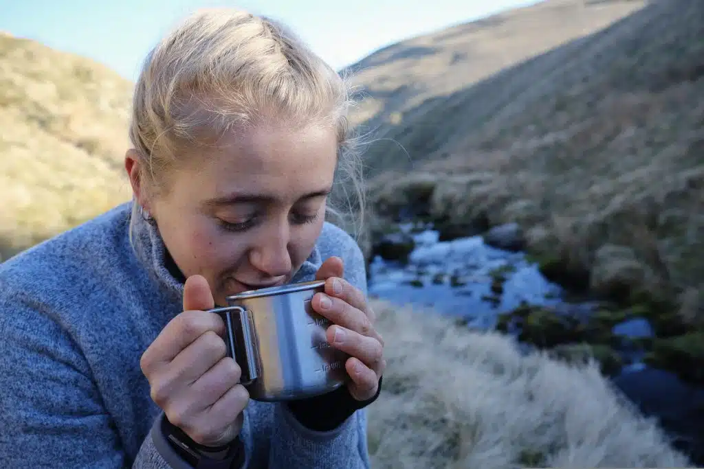 hiker drinking tea by a river